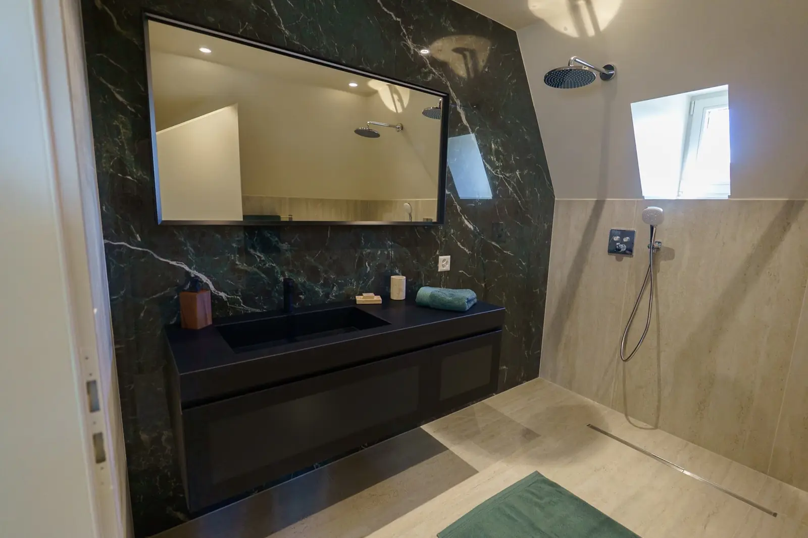 Salle de bain en marbre vert sombre avec miroir lumineux