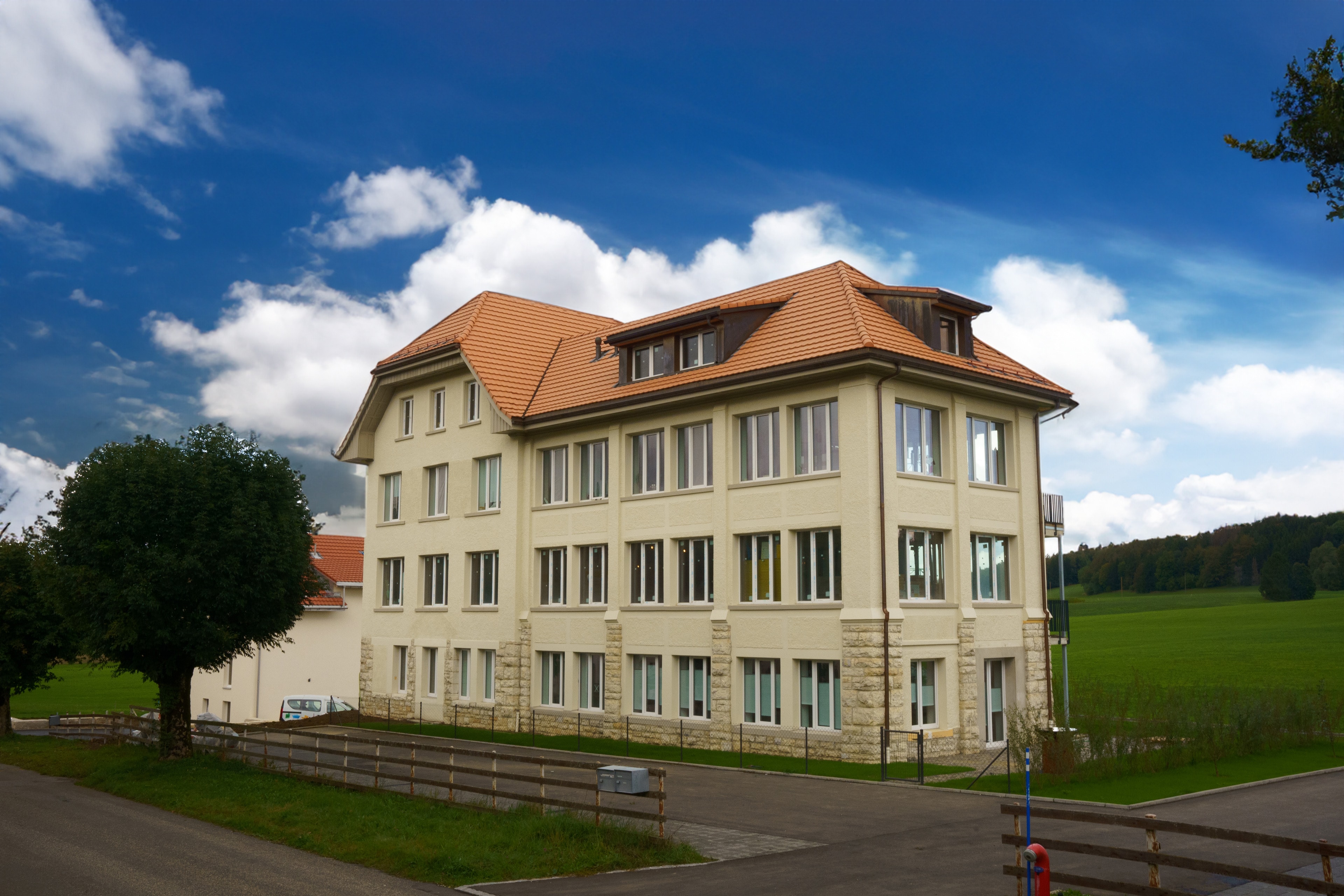 Large light-coloured building surrounded by greenery