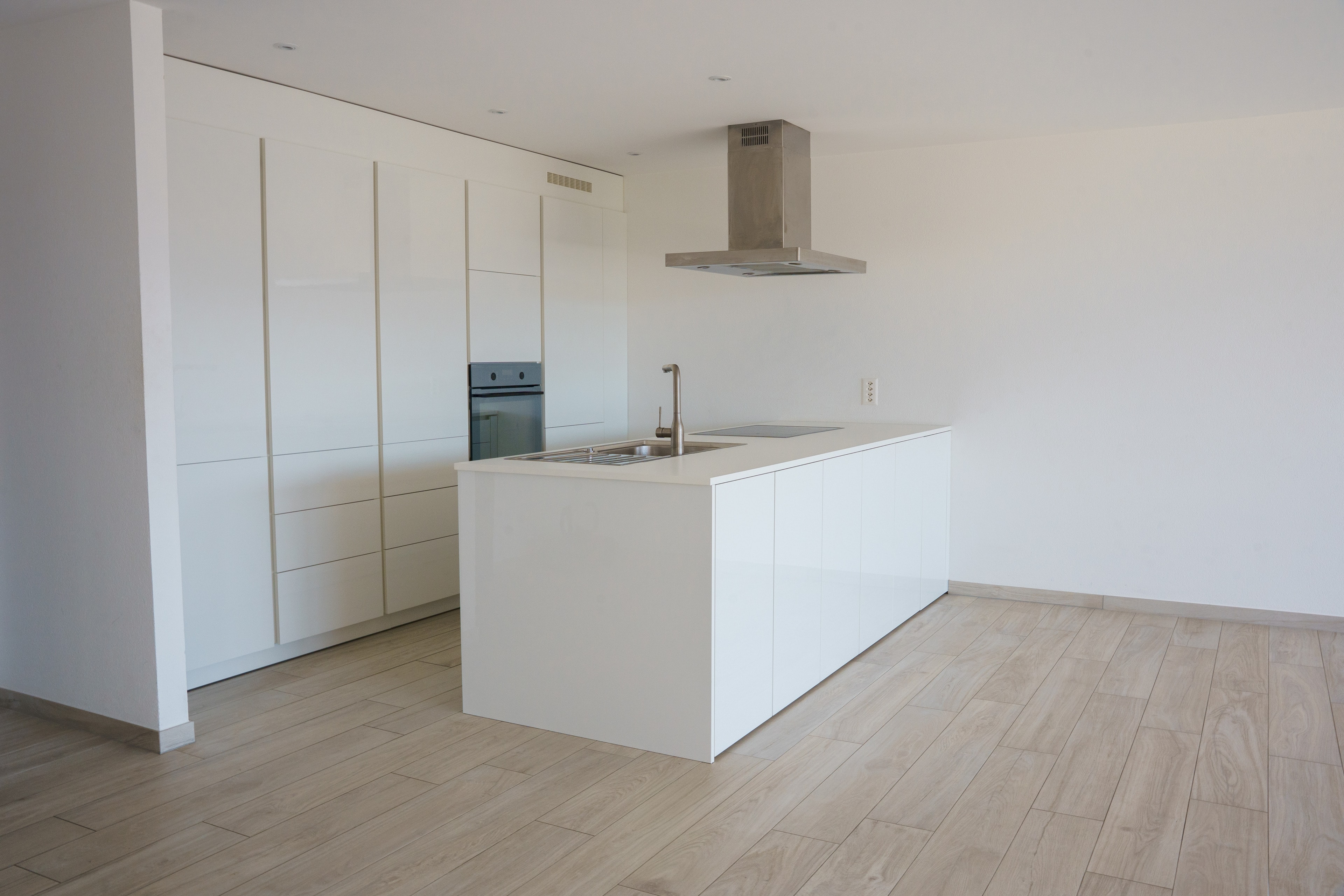 Contemporary white kitchen with an island and light parquet