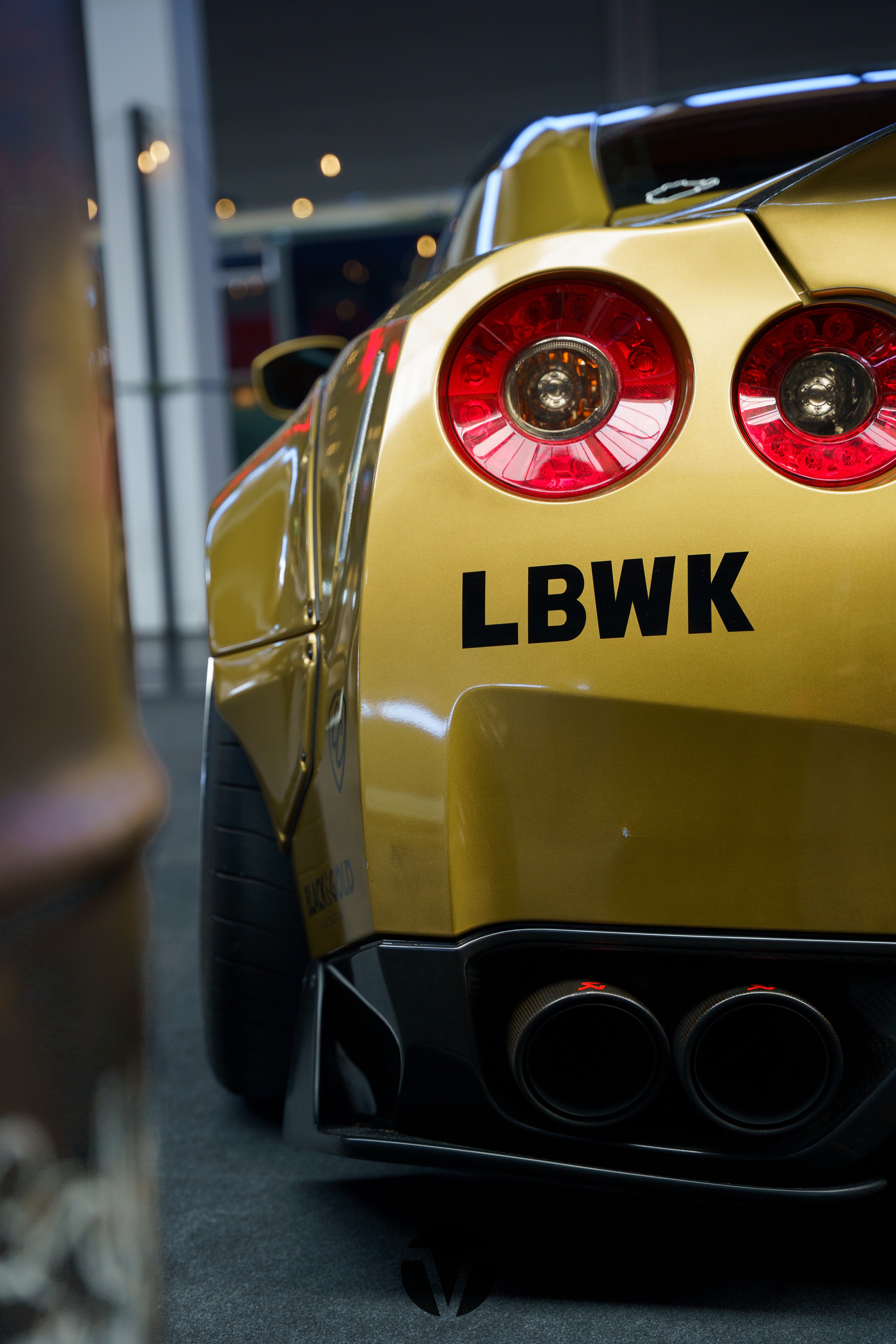 Tail lights of a gold Nissan GT-R with a Liberty Walk kit