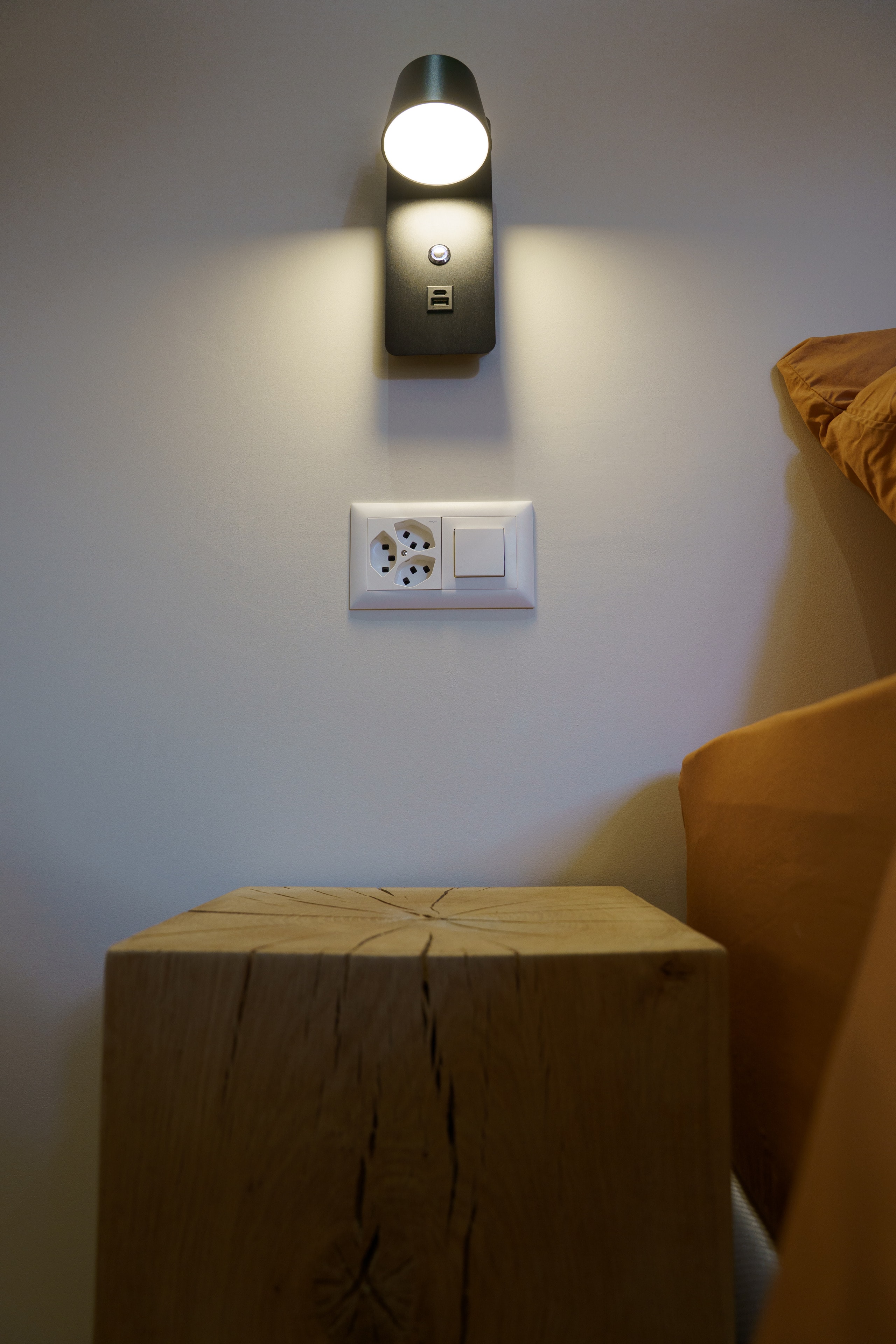 Wall light on above a wooden bedside table