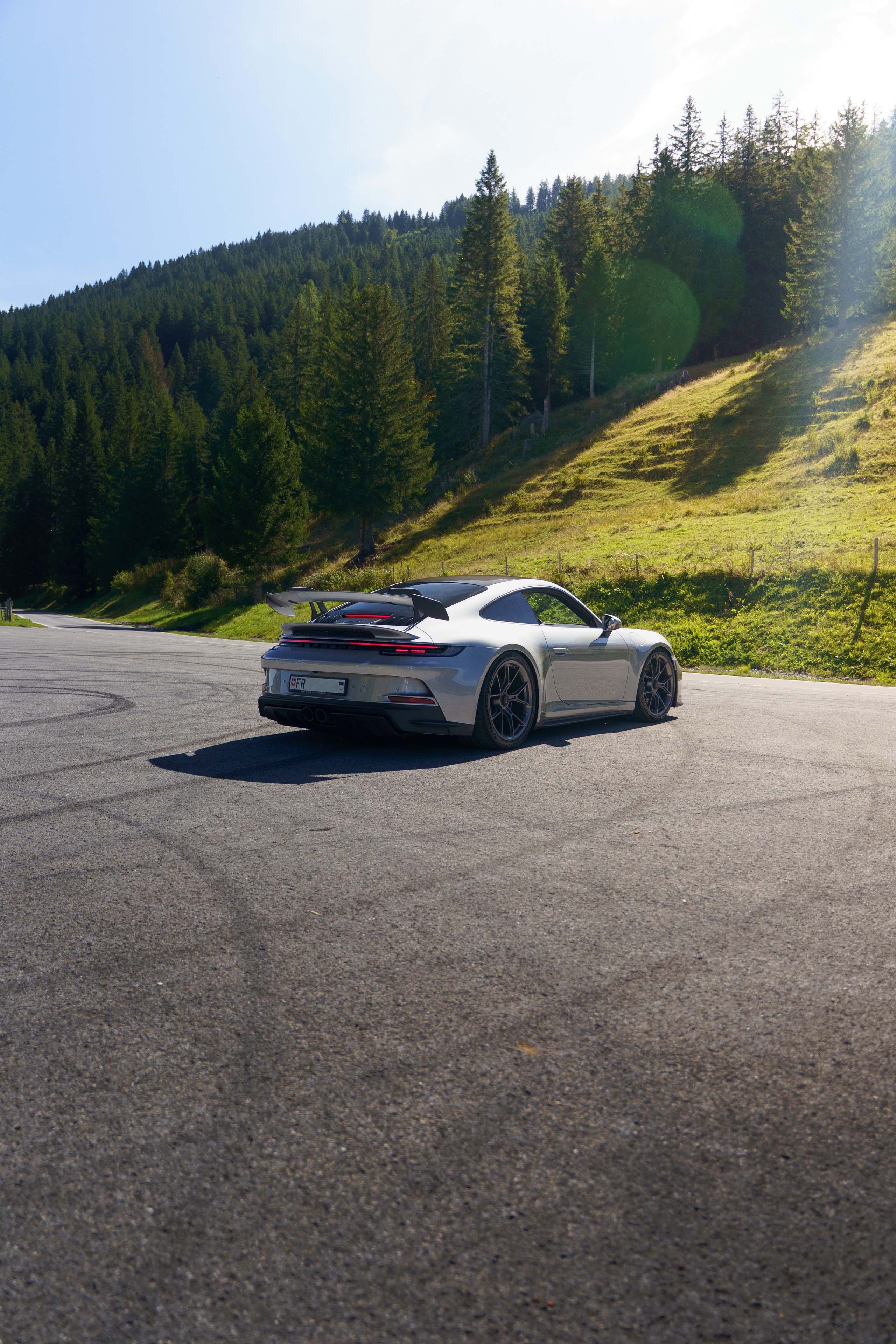 Grey Porsche 911 GT3 in a bend, forest behind